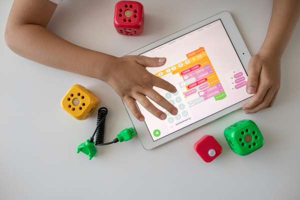 Photo of a child's hands creating code on a tablet