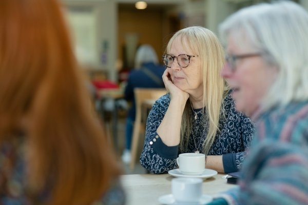 Group of adults sat at a table with coffee