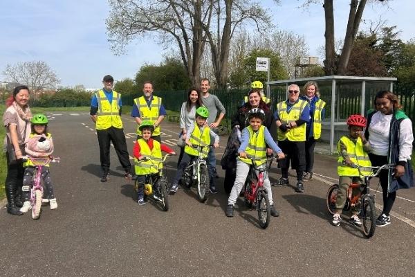 A group young children with their bikes and cycling instructors, wearing high-vis and helmets