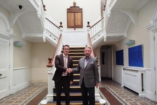 Cllr Jonathan Bianco and Keith Smith, CEO of HRUC, shake hands at the foot of the staircase of Barra Hall to mark the completed sale