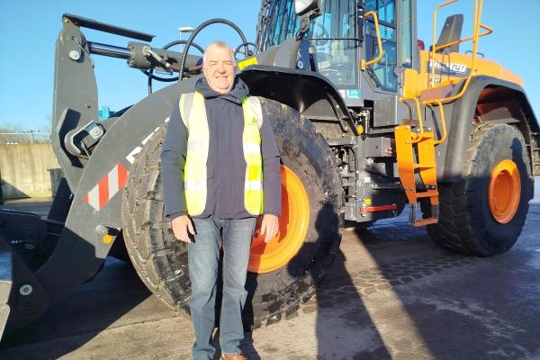 Cllr Eddie Lavery stands in front of a new Develon shove at the Harefield Civic Amenity Site.