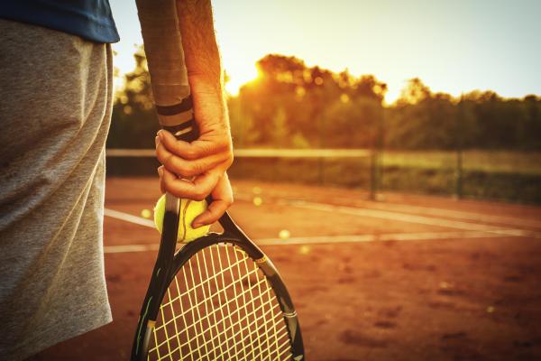 Photo of a person standing on a tennis court, with racquet in hand, ready to play