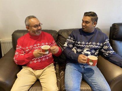 Two people sitting on a sofa drinking tea