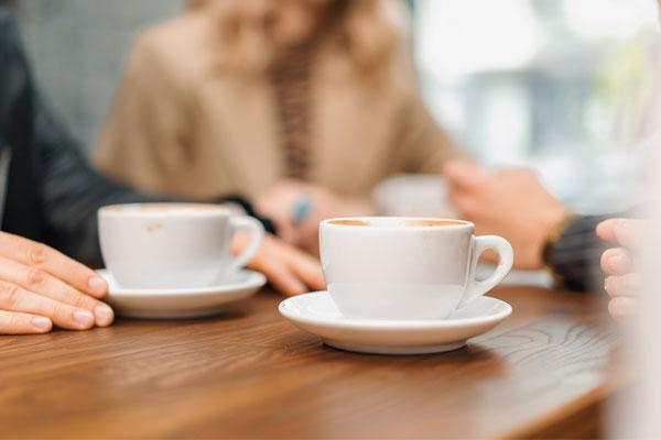cups of coffee on a table with people sat around
